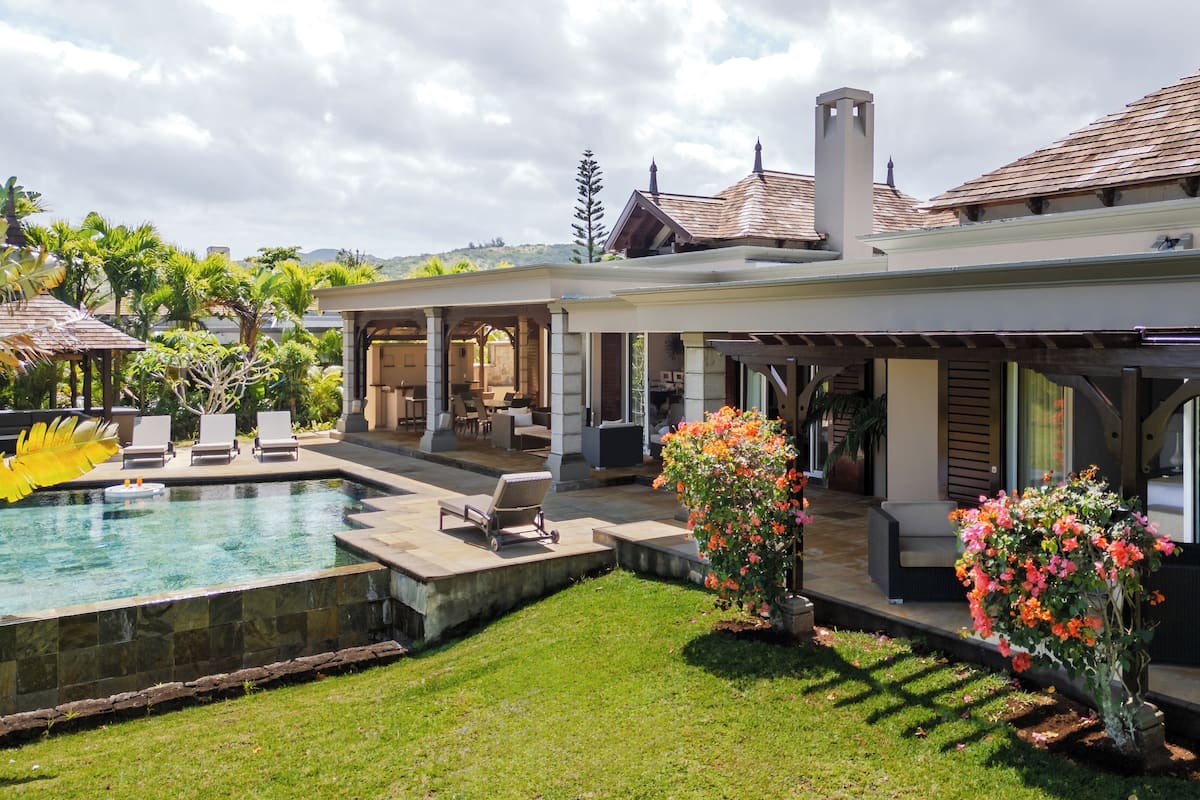 Une maison moderne dotée d’une piscine, d’un espace salon extérieur et d’un jardin bien entretenu.