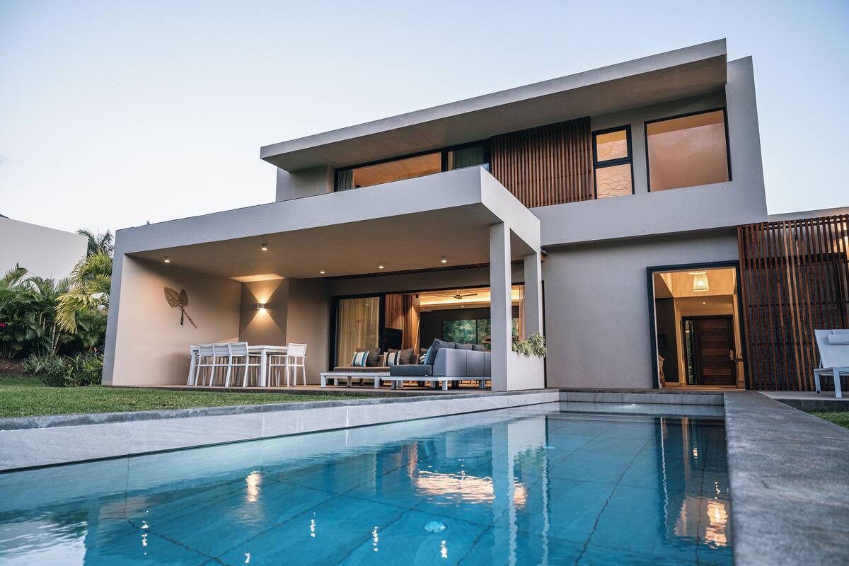 Une maison moderne à deux étages dotée d’une piscine, d’un espace salon extérieur et d’un patio couvert.