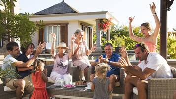 A group of people seated on wicker furniture outdoors, with a house in the background.