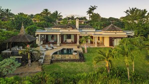 A large house with a swimming pool, surrounded by lush greenery and palm trees.