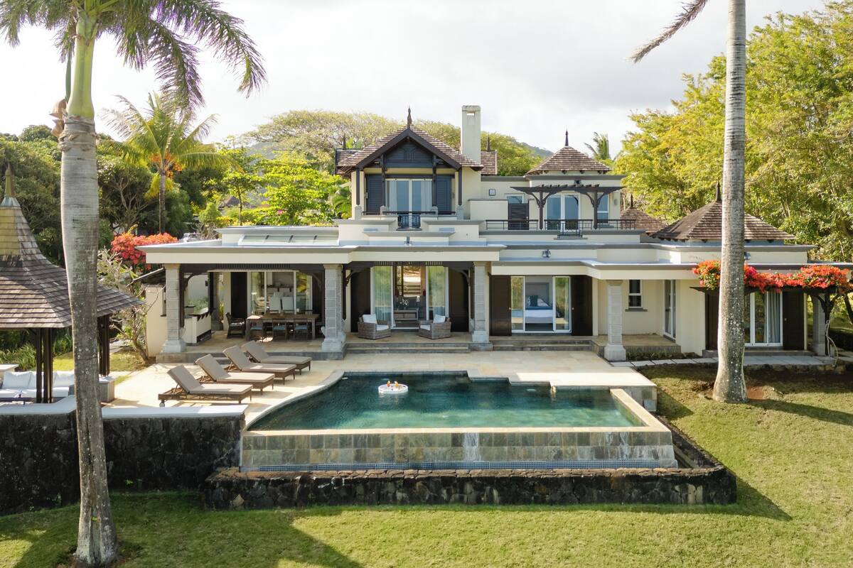 Une grande maison à deux étages dotée d’une piscine, d’un espace salon extérieur et d’un belvédère.