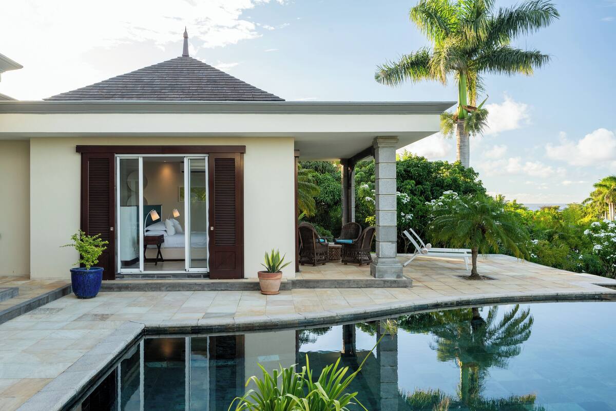 Une maison moderne dotée d’une piscine, d’un patio avec mobilier d’extérieur et offrant une vue sur la verdure environnante.