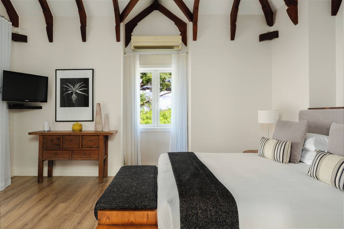 Une chambre à coucher avec un lit, une table de chevet, une télévision et une fenêtre avec des rideaux.
