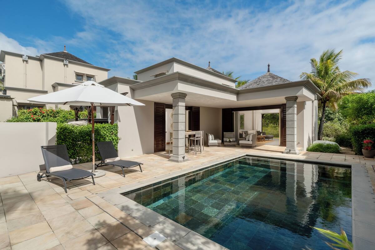 Une maison moderne dotée d’une piscine, d’un espace salon extérieur et d’un patio couvert.
