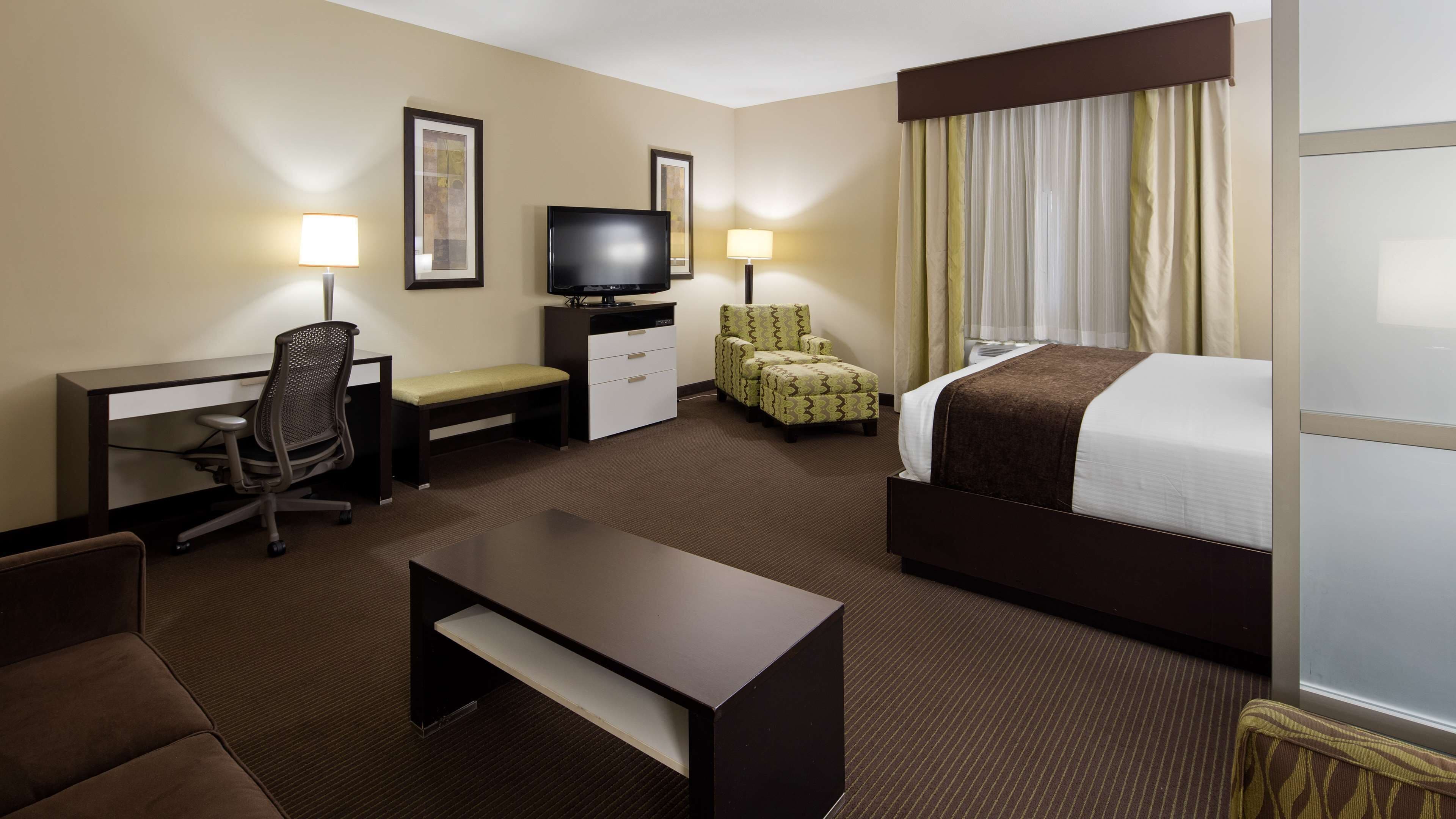 Une chambre d’hôtel équipée d’un lit, d’un bureau, d’une chaise, d’une télévision et d’une lampe.