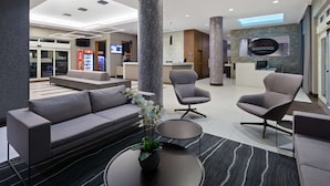 A modern lobby with a sofa, armchairs, a reception desk, and a large pillar. - Best Western Plus Miami Intl Airport Hotel & Suites Coral Gables (Miami)
