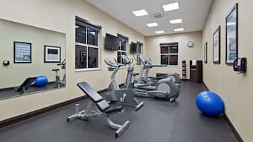 Un gimnasio con equipo de ejercicio, un espejo y un reloj en la pared.