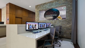 A reception area with a stone wall, a sign for '4100 Restaurant & Lounge', and three computer monitors on a desk. - Best Western Plus Miami Intl Airport Hotel & Suites Coral Gables (Miami)