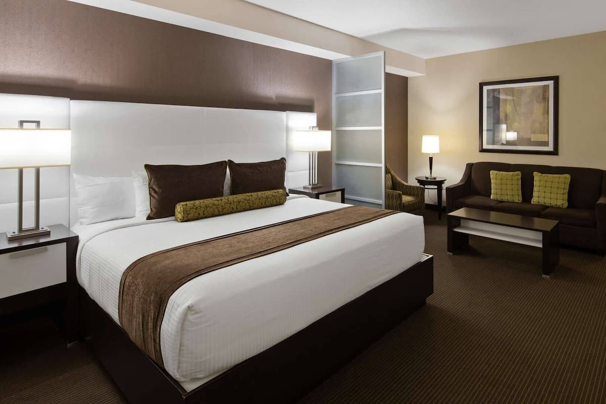 A hotel room with a large bed, a sofa, a coffee table, a desk, and a chair.