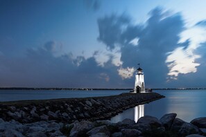 Un faro en una costa rocosa con aguas tranquilas que reflejan la estructura.