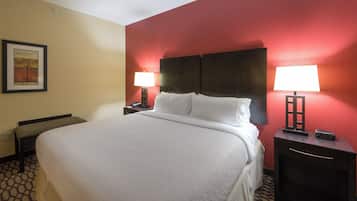 Habitación de hotel con una cama grande, dos mesitas de noche con lámparas, un cuadro enmarcado en la pared y un suelo con estampado.