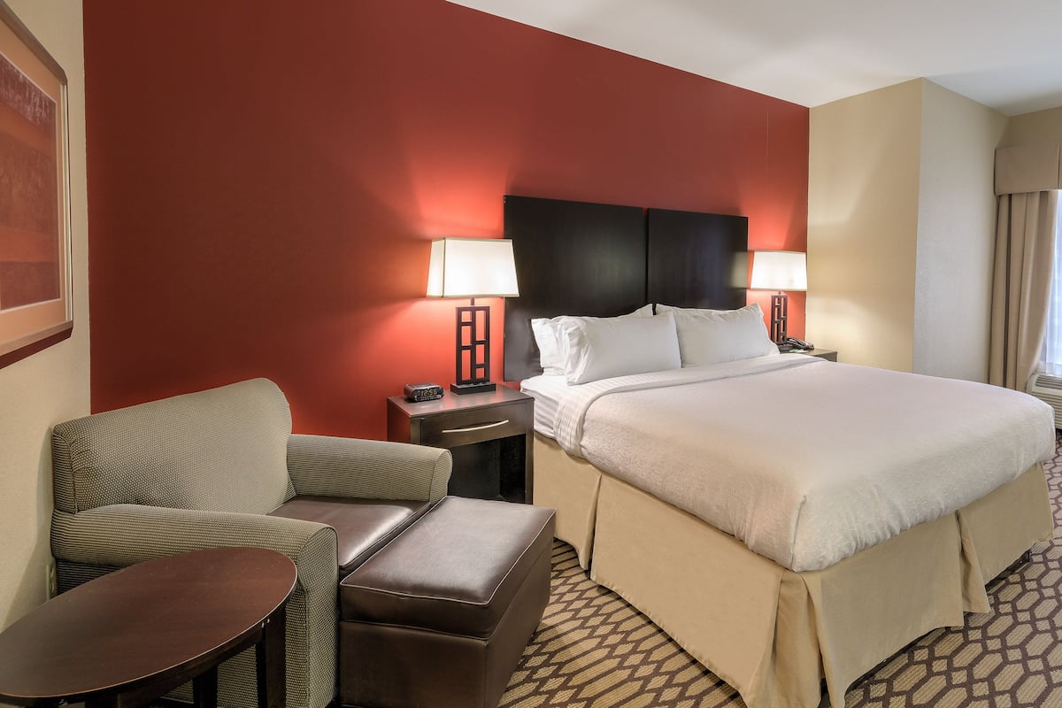 A hotel room with a bed, two bedside tables, a chair, and a desk.