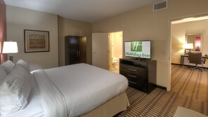 Una habitación de hotel con una cama, un escritorio con un televisor que muestra el logotipo de Holiday Inn, un armario y un baño visible a través de una puerta abierta.