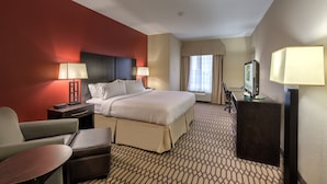 A hotel room with a bed, a desk, a chair, a TV, and a lamp.