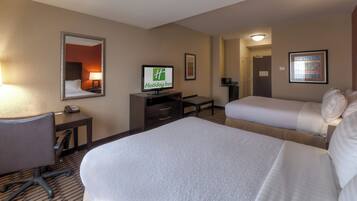 A hotel room with two beds, a desk with a computer, a telephone, and a television displaying the Holiday Inn logo.