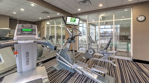 Une salle de sport d’hôtel équipée de matériel d’exercice, dotée d’un écran numérique et arborant l’enseigne Holiday Inn.