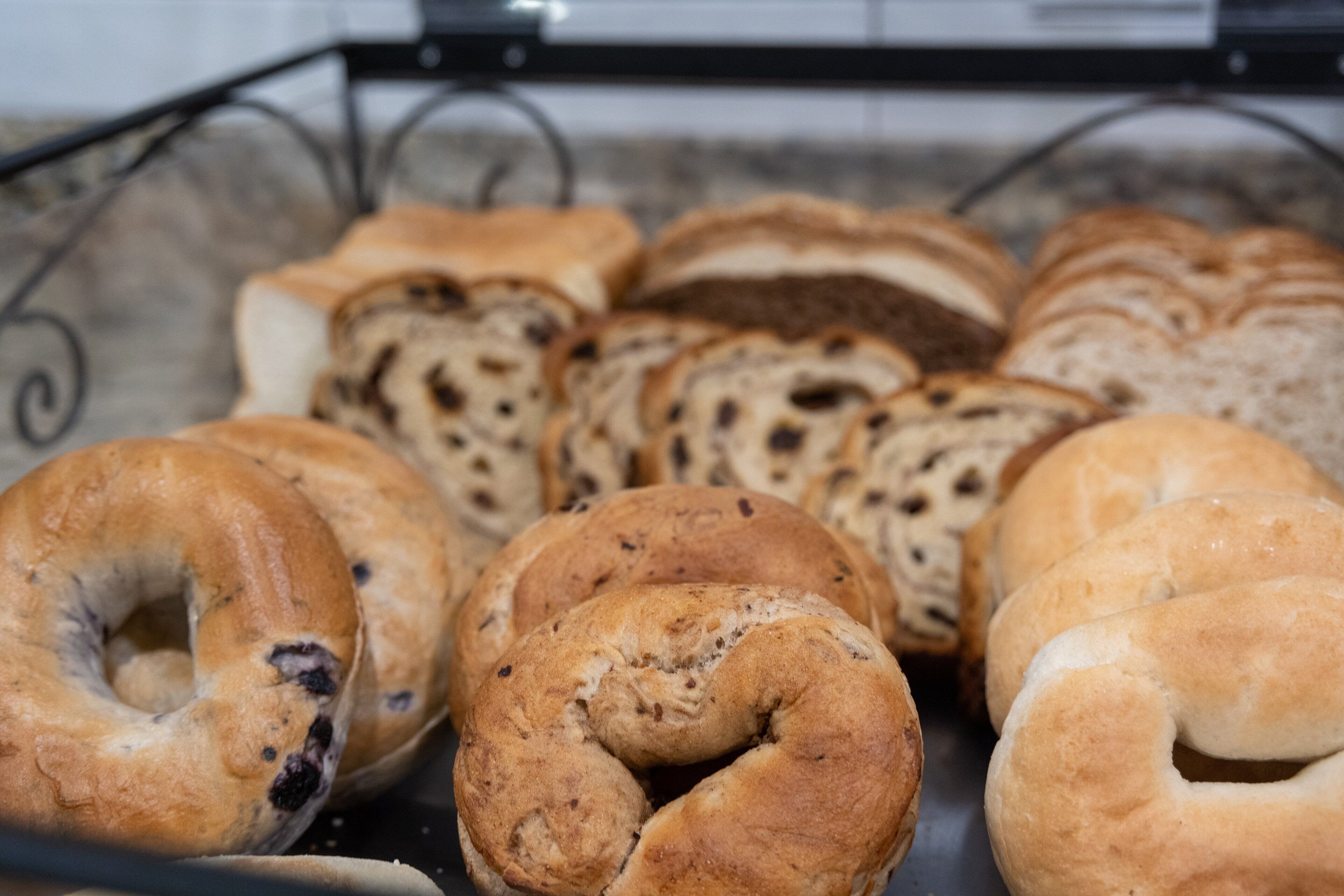 A variety of bagels arranged on a metal rack.