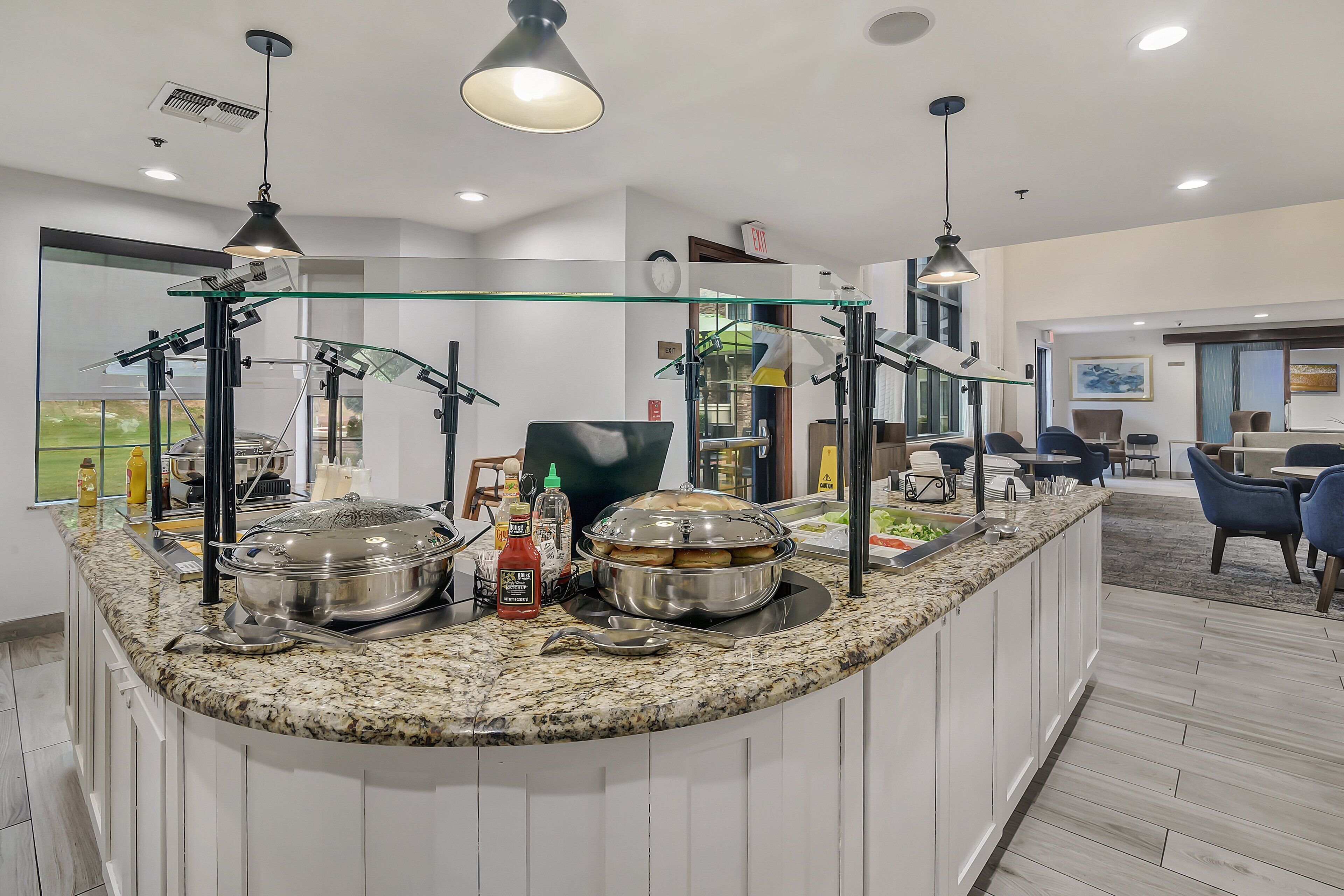 A modern kitchen with a granite countertop, stainless steel appliances, and a glass partition.