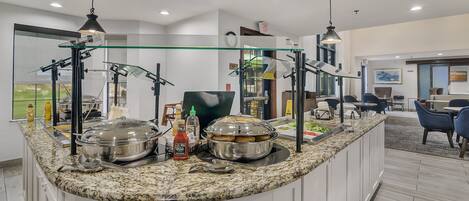 A modern kitchen with a granite countertop, stainless steel appliances, and a glass partition.