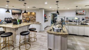 Eine moderne Küche mit Granit Arbeitsplatten, Barhocker und einer Steinrückwand.
