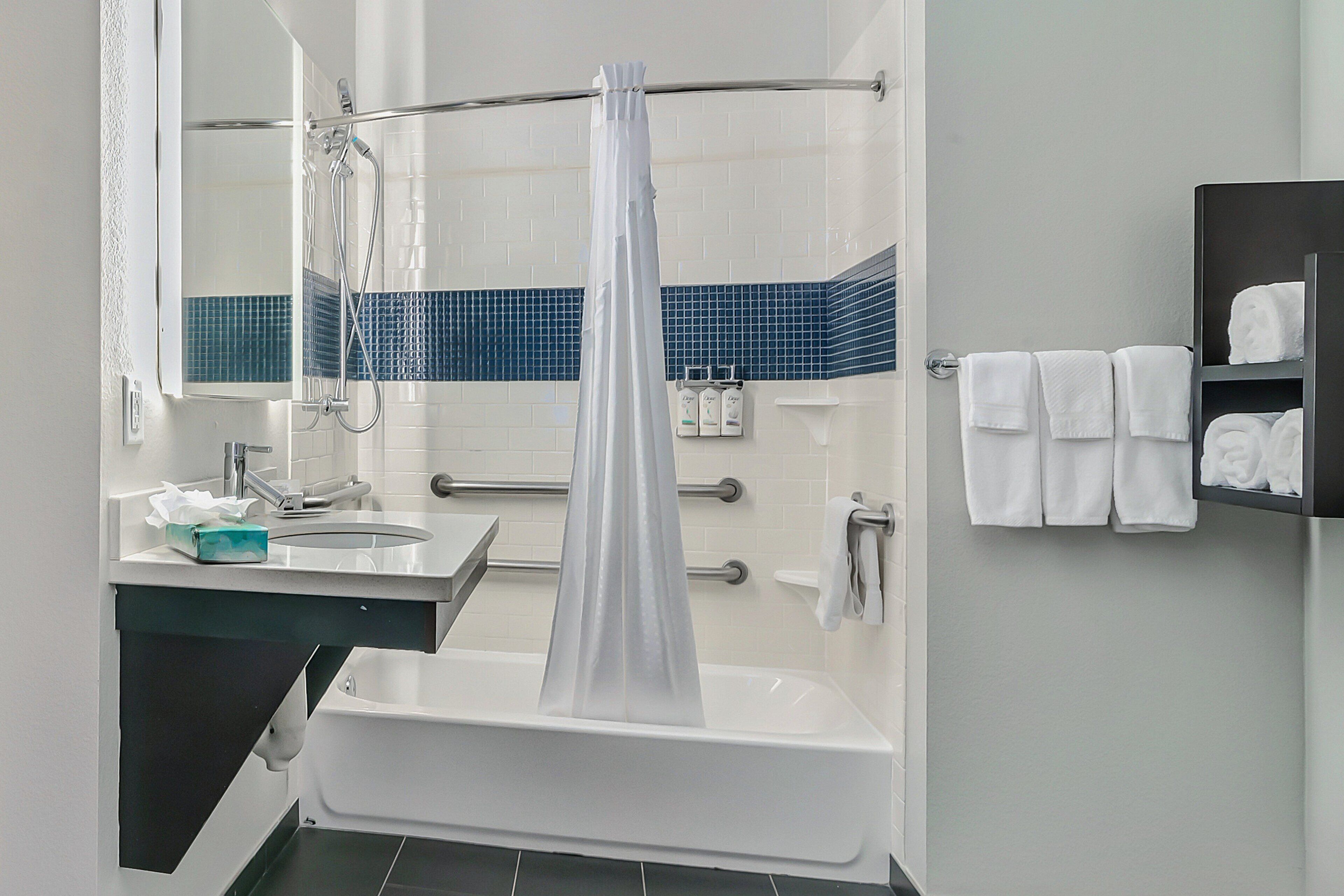 A bathroom with a bathtub, a shower, a sink, and a towel rack.