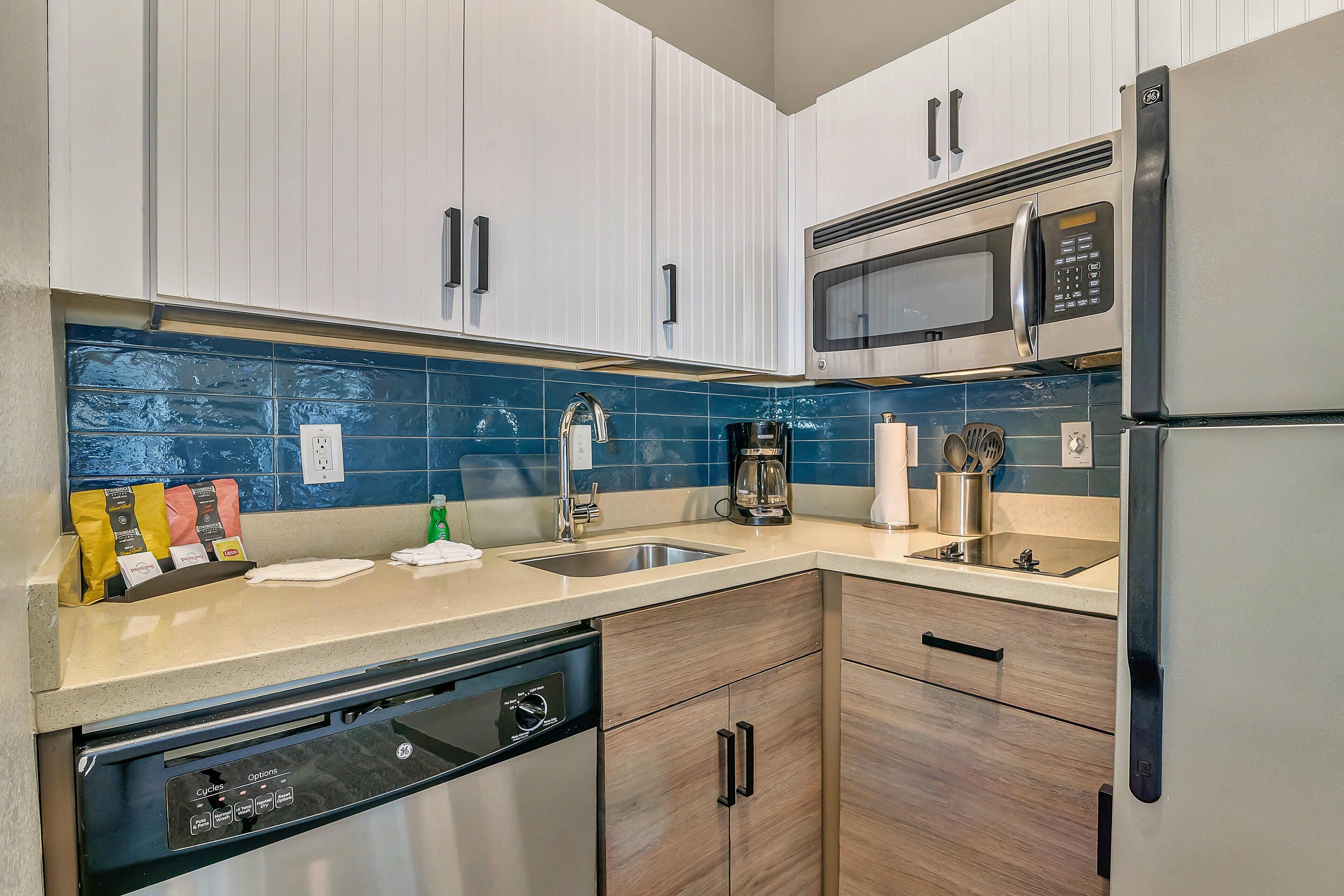 A modern kitchen with white cabinets, a stainless steel refrigerator, a microwave, and a dishwasher.