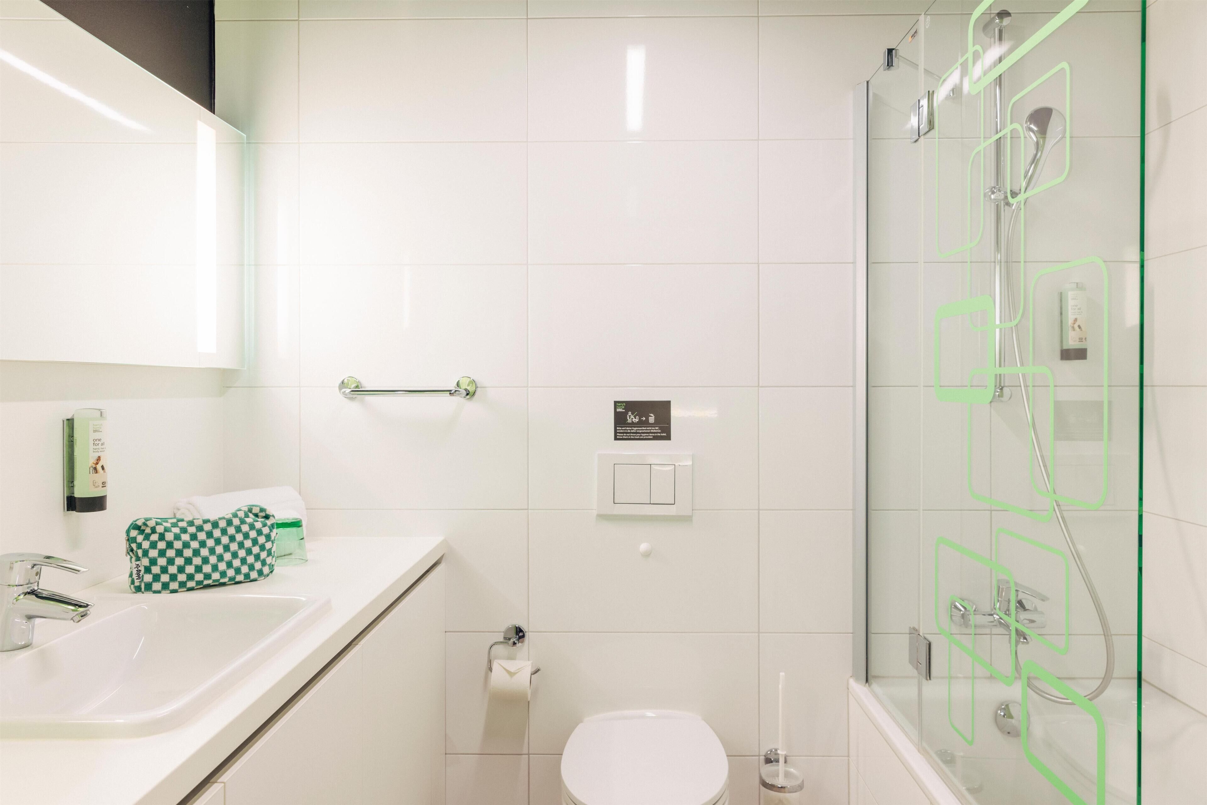 Un baño moderno con ducha de vidrio, lavamanos blanco y un inodoro.
