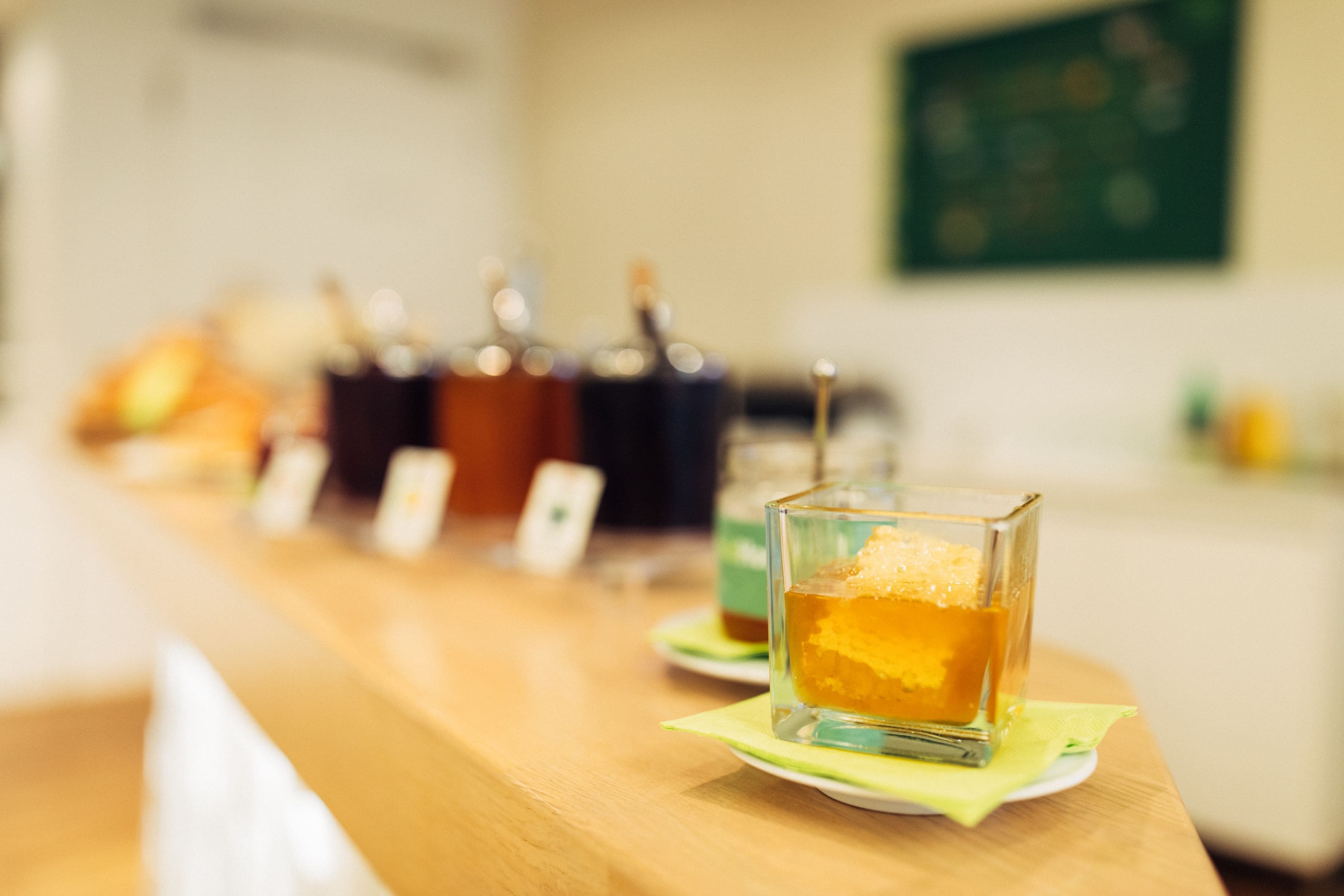Uma área de bar com diversas bebidas e um copo de bebida cor de âmbar sobre um tabuleiro.