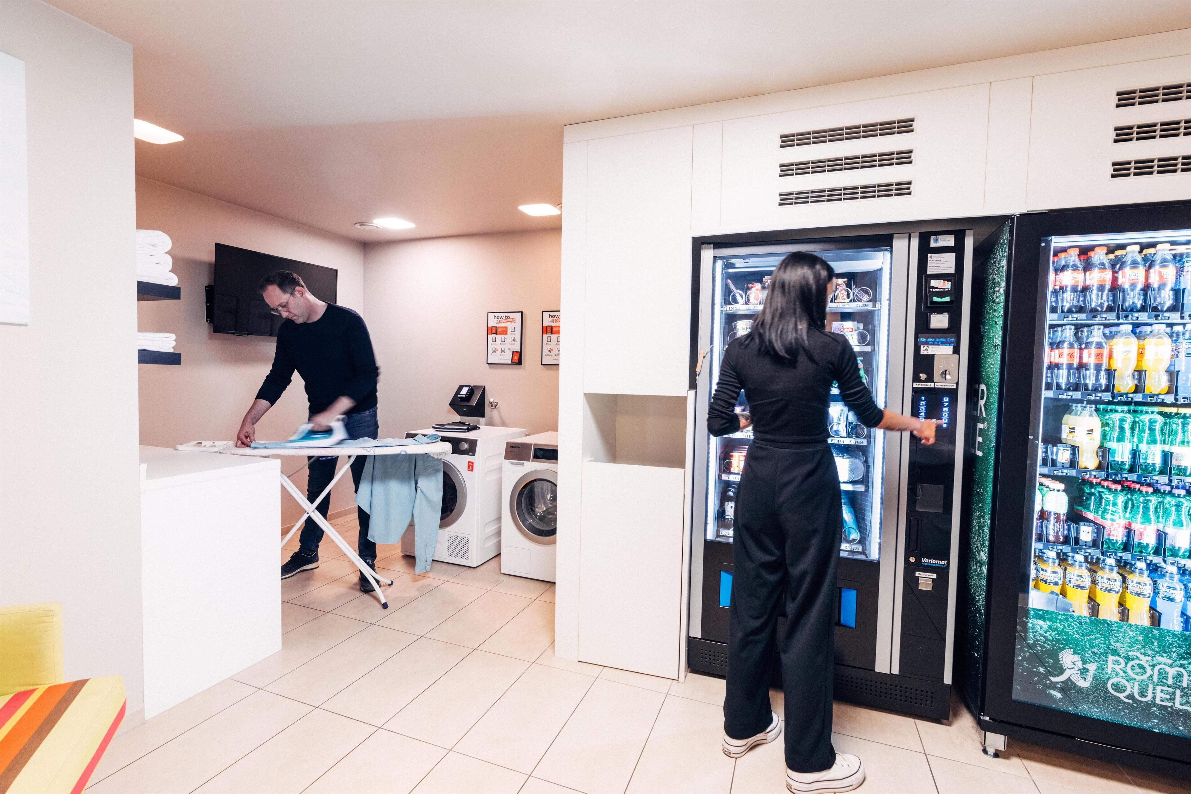 A laundry area with a washing machine, dryer, and ironing station.