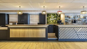 Zona bar moderna con un bancone in legno, pensili neri e una parete verde con la scritta 'Be distenn'.