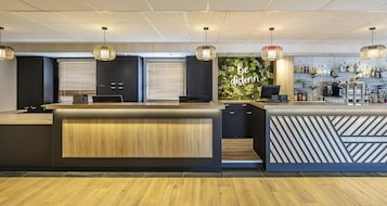 Un área de bar moderna con un mostrador de madera, armarios negros y una pared verde con la inscripción 'Be distenn'.