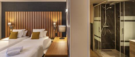 Een hotelkamer met twee bedden, een houten hoofdbord, bedlampen en een houten tafel.