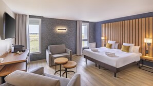 Una camera d'albergo con un letto, una scrivania, una sedia, un tavolino e una televisione.