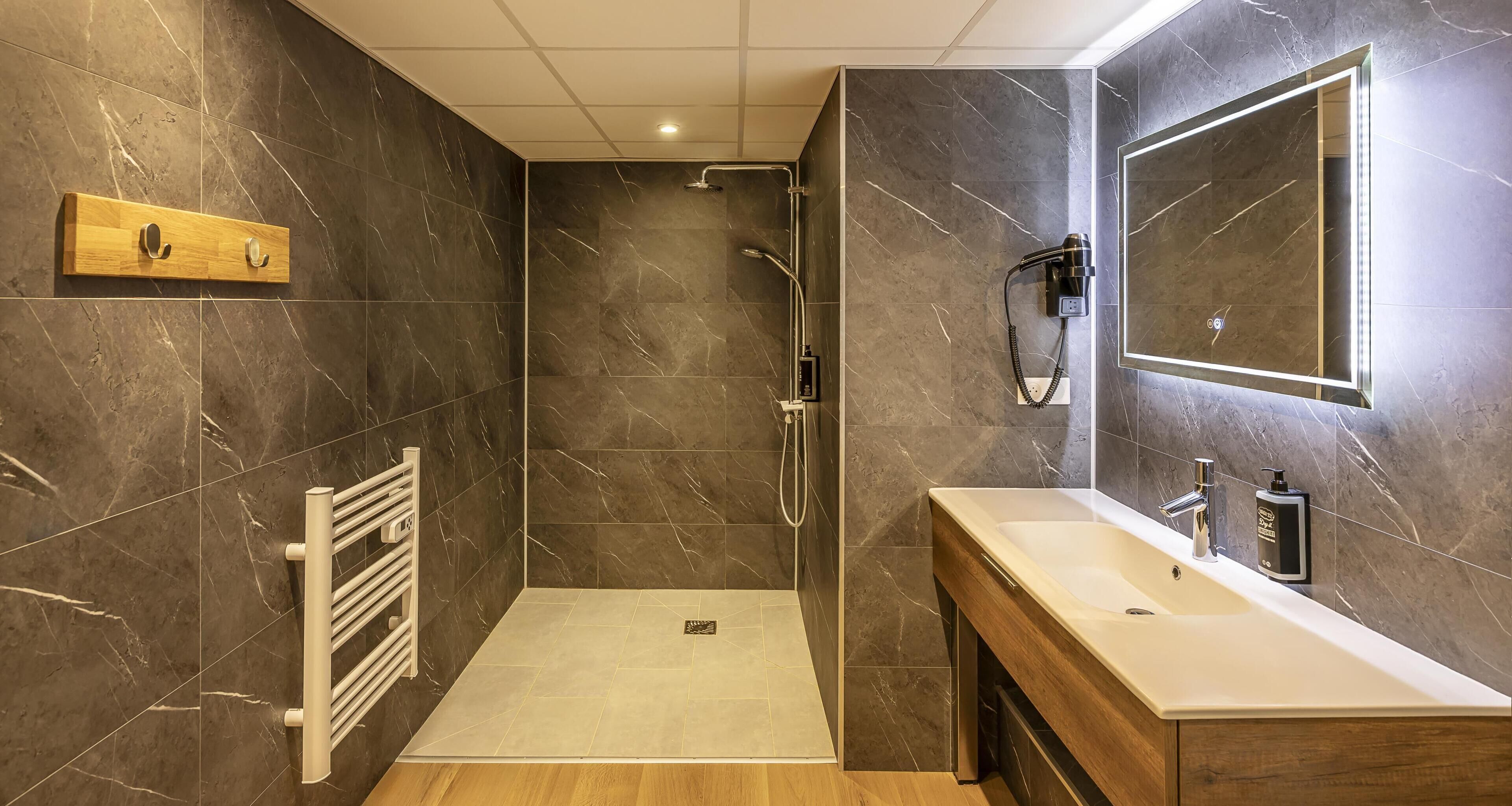 Un baño moderno con ducha, tocador y espejo.