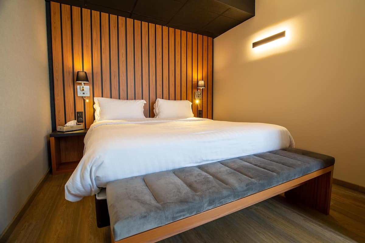 Un lit avec une tête de lit, des lampes de chevet et un plancher en bois.