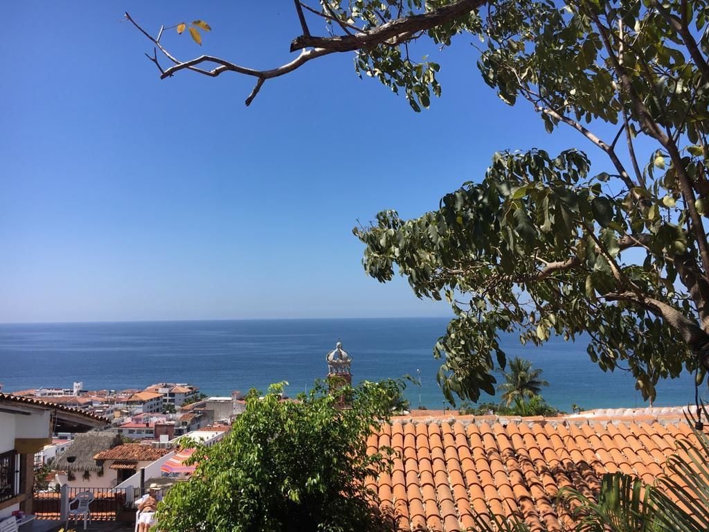 Eine Küstenstadt mit Terrakotta-Dächern, blauem Himmel und Blick auf das Meer.