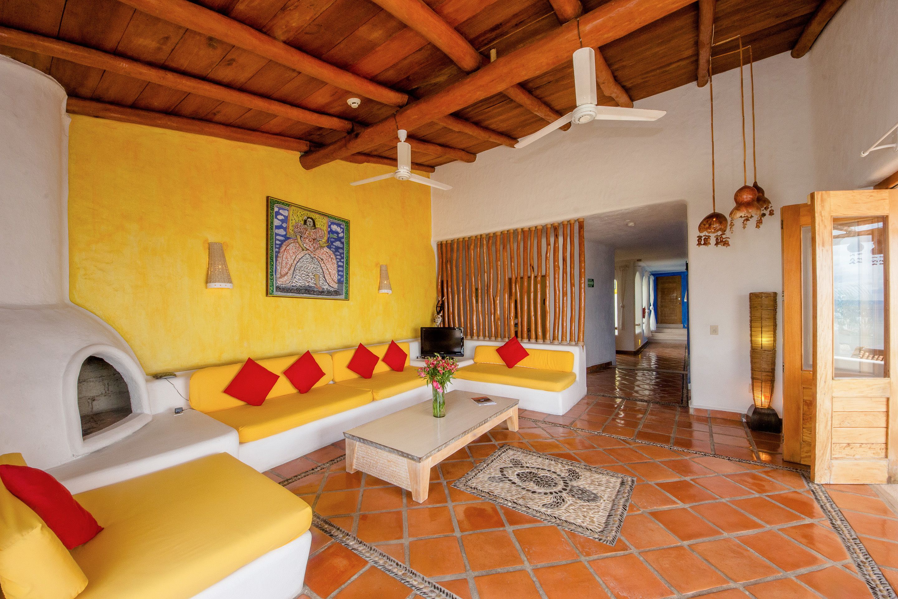 Una sala de estar con un sofá amarillo, una chimenea y un techo de madera.