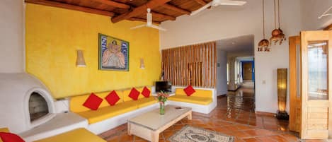 Una sala de estar con un sofá amarillo, una chimenea y un techo de madera.