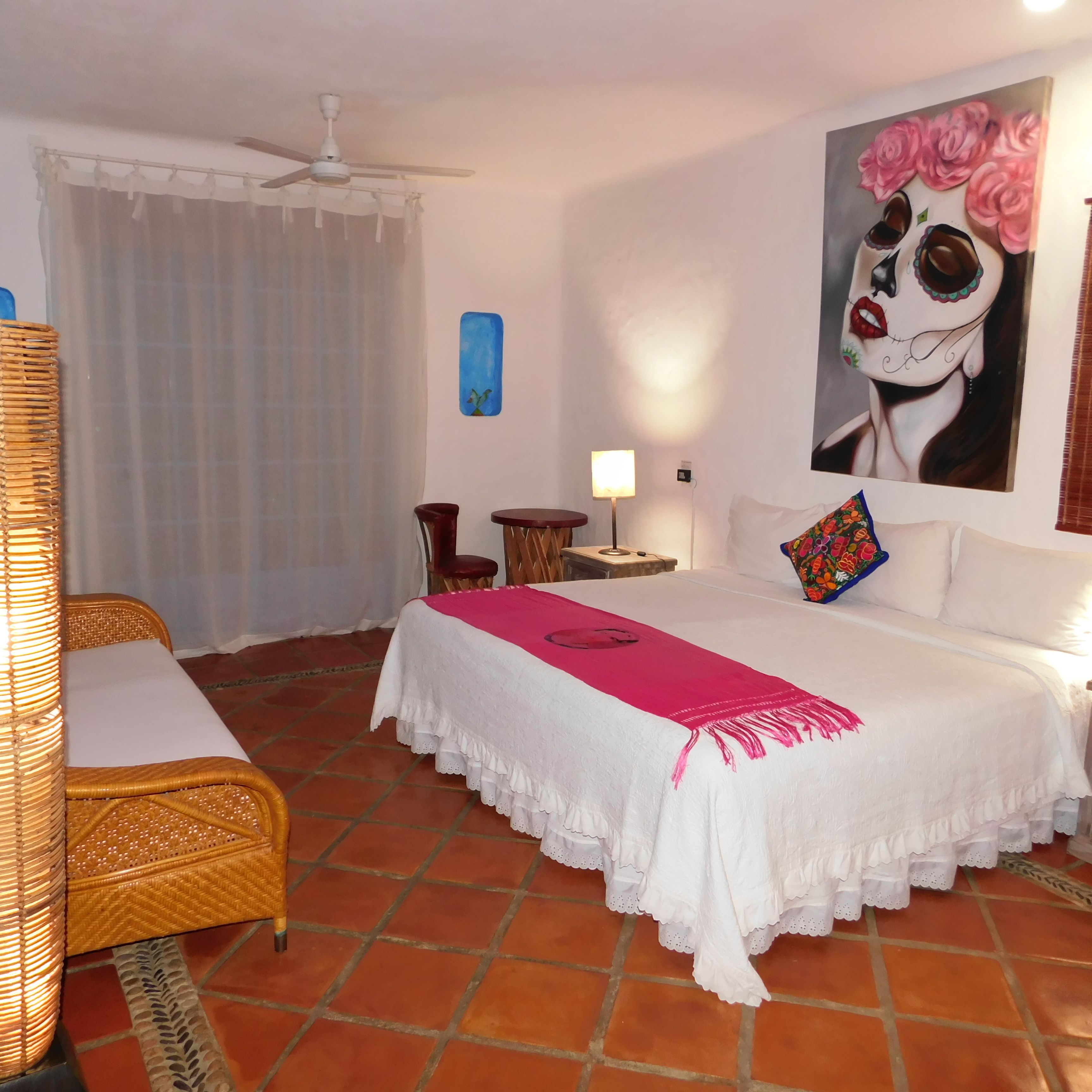 Une chambre d’hôtel avec un lit, une chaise, une table de chevet, une lampe et un tableau au mur.