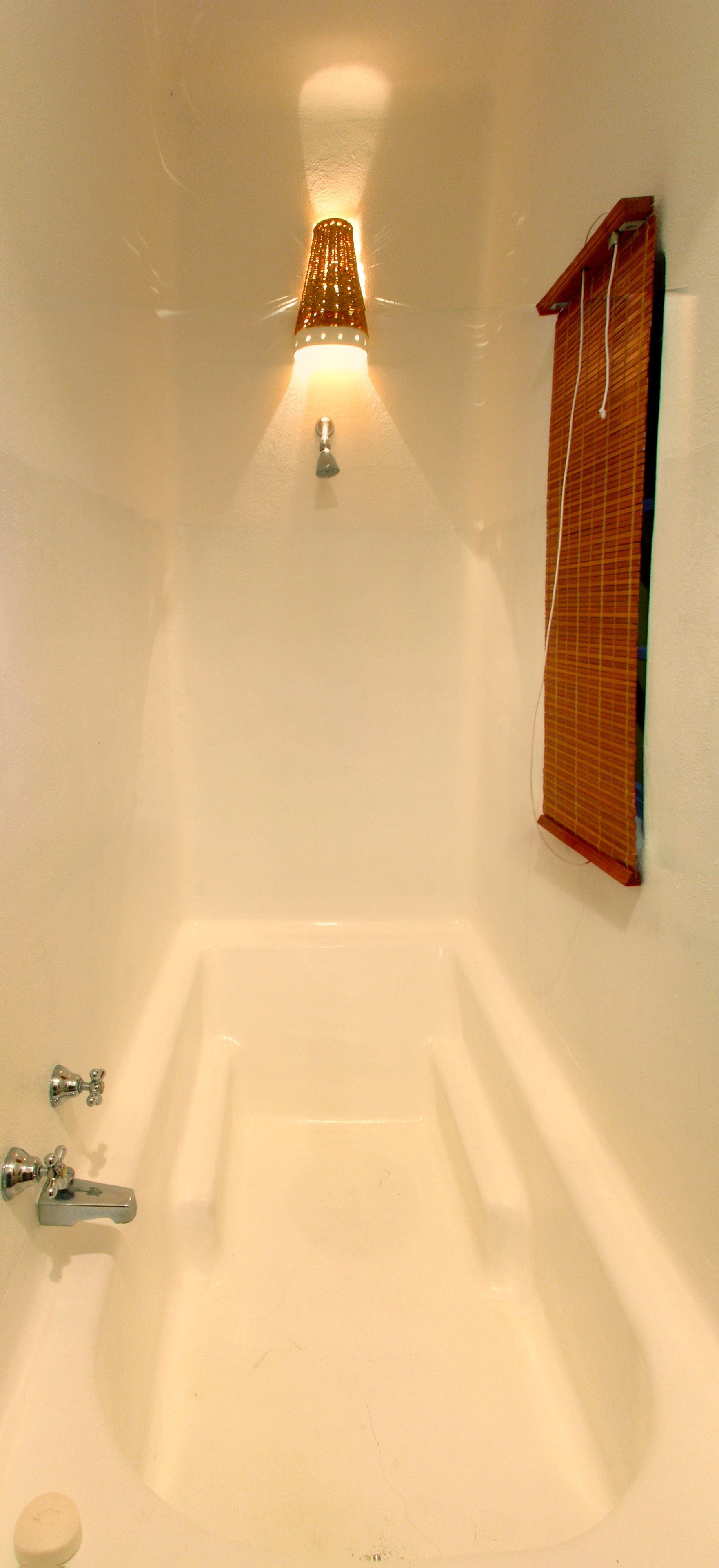 A bathroom with a bathtub, a wall-mounted towel rack, and a light fixture above the tub.
