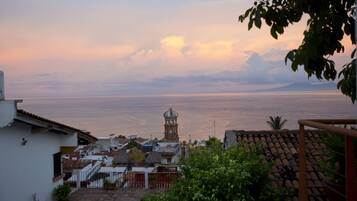 A coastal town with a prominent clock tower, terracotta rooftops, and a view of the sea.