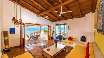 A spacious living area with a wooden ceiling, a sofa, a coffee table, and a fireplace.