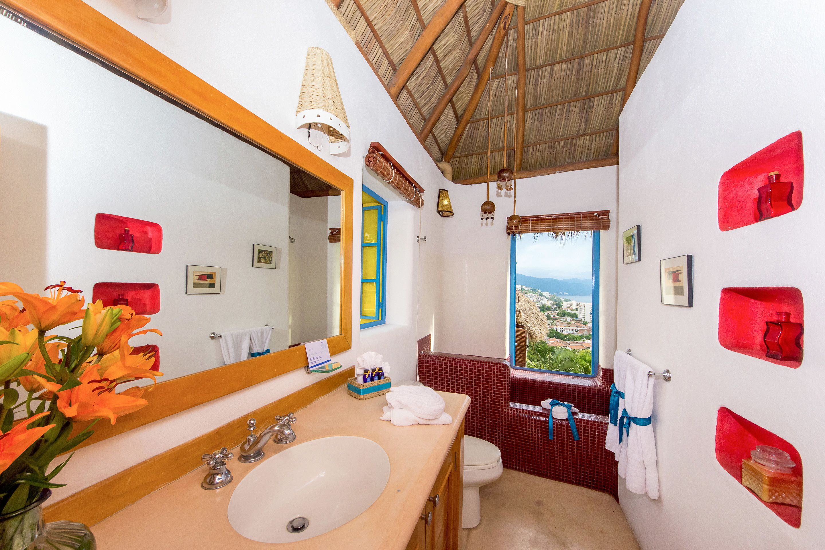 Un baño con un espejo grande, un lavabo, un inodoro y una ventana con vistas.
