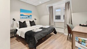 Ein modernes Hotelzimmer mit Bett, Schreibtisch und einem Fenster mit Vorhängen.