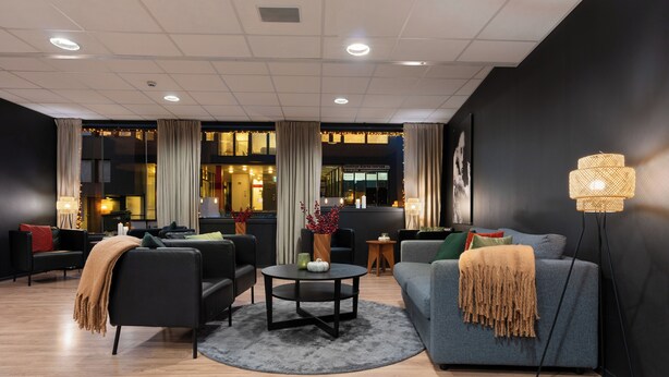 Ein stilvolles Wohnzimmer mit einer Couch, Sesseln, einem Couchtisch und einer Stehlampe.