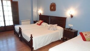 Una cama doble con cabecera de madera, dos mesitas de noche y una mesita auxiliar con lámpara.