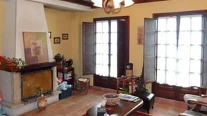 Una sala de estar acogedora con chimenea, vigas de madera y ventanas amplias.