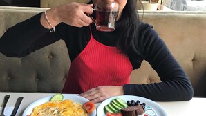 Une personne est assise à une table devant un repas composé d’œufs, de pain, de légumes et de yaourt.