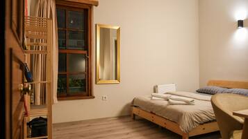 Quarto com cama de madeira, mesa de cabeceira, espelho e janela com cortinas.