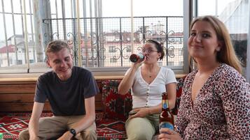 Three people sitting on a bench with a view of buildings through a window.